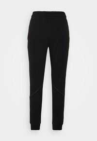 Pantalones de chándal negros con cintura elástica, tobillos ajustados y costuras de contraste a lo largo de las costuras laterales, presentando una textura suave.