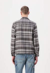 Grå rutete skjorte med lange ermer og knappmansjetter, laget av mykt stoff. Den har en standard revers og en løs passform.