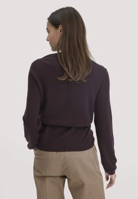 Strickpullover in Dunkellila mit langen Ärmeln, einem runden Halsausschnitt und einer figurschmeichelnden Passform an der Taille. Weiche Textur mit glatter Oberfläche.