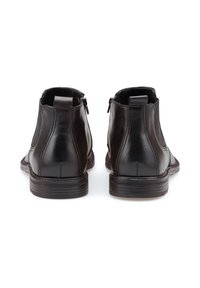 Bottines en cuir noir avec une finition lisse, des zips sur les côtés et un talon bas. Elles présentent un design élégant et des détails cousus le long des coutures.