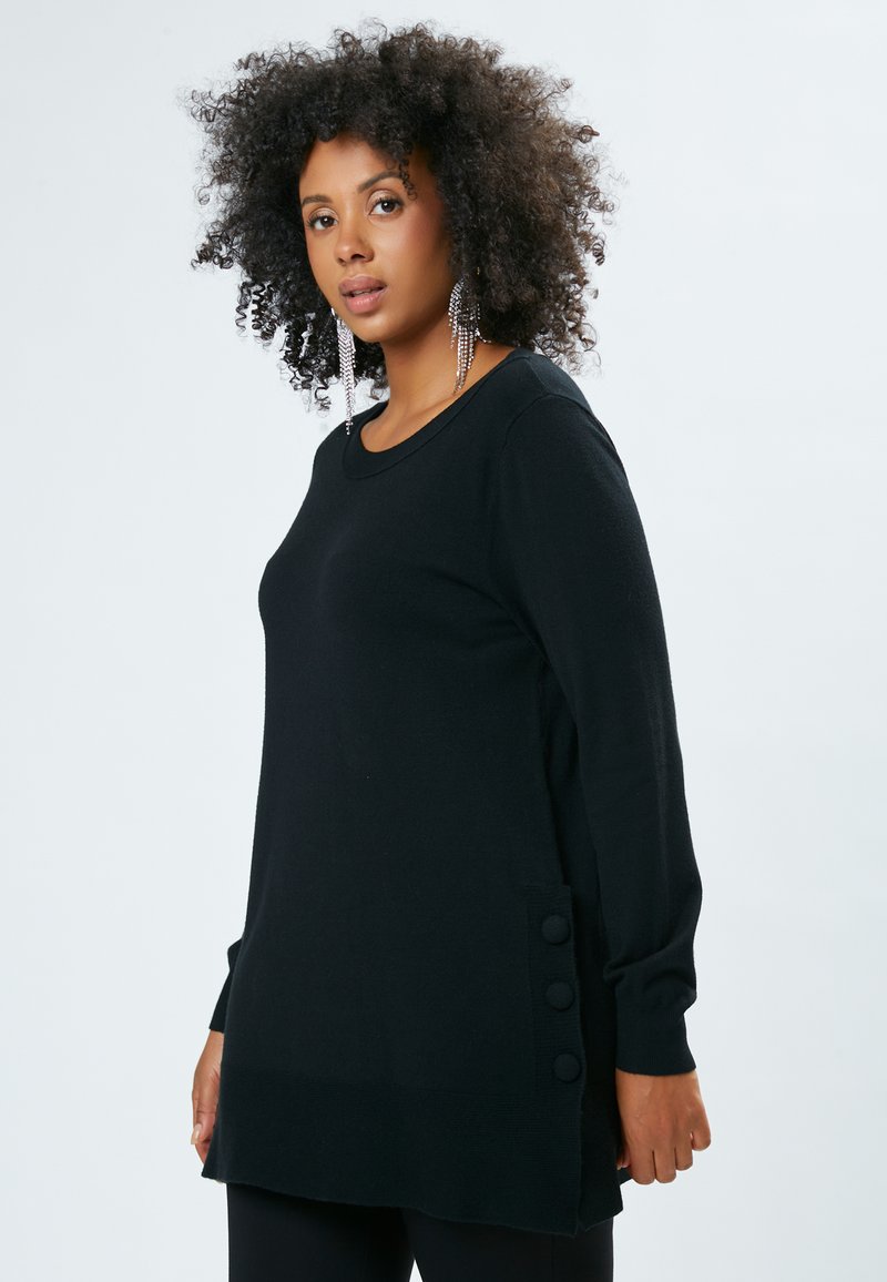 Maglione nero a maniche lunghe con scollo tondo e tre bottoni decorativi sul lato, realizzato in materiale morbido e testurizzato.