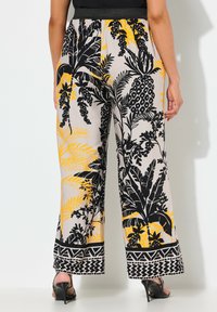 Kalhoty s širokými nohavicemi v květinovém vzoru, které obsahují černou, žlutou a béžovou barvu. Elastický pas s podrobným designem zakončení.