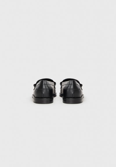Svarta läderskor med en slät textur, låg profil och rundad tådesign. Har en slip-on stil med diskreta sömnadsdetaljer.