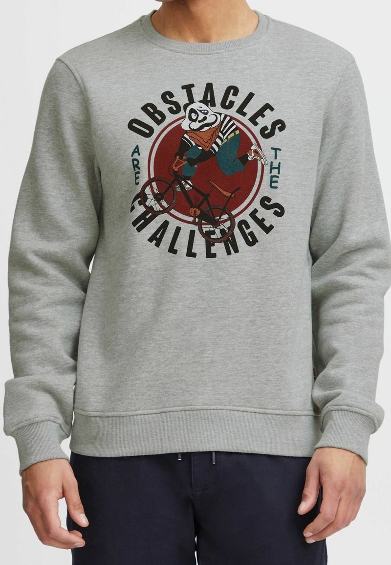 Szary sweatshirt z grafiką pandy na rowerze, z wyboldowanym napisem "Przeszkody są wyzwaniem". Miękka tekstura, okrągły dekolt.
