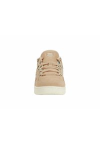 Beige mockasinsneakers i mocka med texturerad yta, rund tå, kontrasterande vit gummisula och snörning. Har en logotyp på tungan.