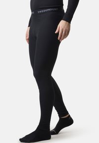 Black thermal leggings with ribbed texture and elastic waistband featuring "SWEDEMOUNT" logo. Fitted design extends to ankles.