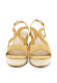 Yellow suede sandals with open toes, a crisscross strap design, and a jute platform sole. Buckle strap at the ankle for secure fit.