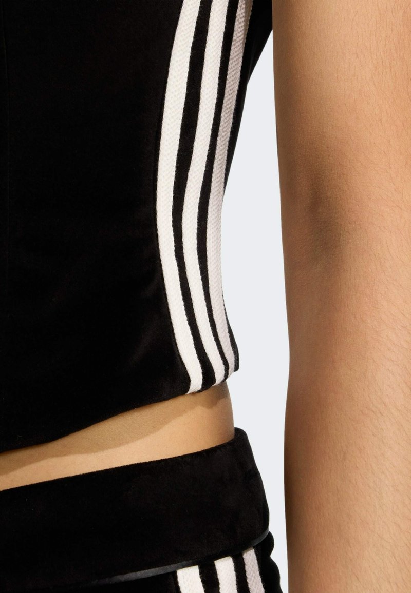 Zwarte cropped top van zachte stof, met witte zijstrepen. Het materiaal heeft een gladde textuur en een slim-fit ontwerp.