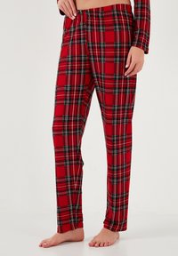 Punat punajat kahdet pyjamat mustilla ja valkoisilla yksityiskohdilla. Valmistettu pehmeästä kankaasta, jossa on joustava vyötärö ja suora lahjemuoto.