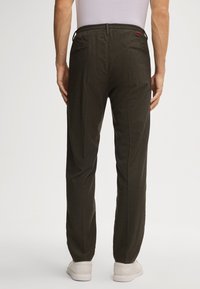 Ciemnozielone spodnie o luźnym kroju, elastyczny pas, boczne kieszenie oraz subtelna tekstura. Stylizowane z białymi sneakersami.