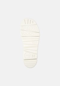White rubber shoe sole with textured patterns, including grooves and waves, featuring a circular logo and size marker "38."