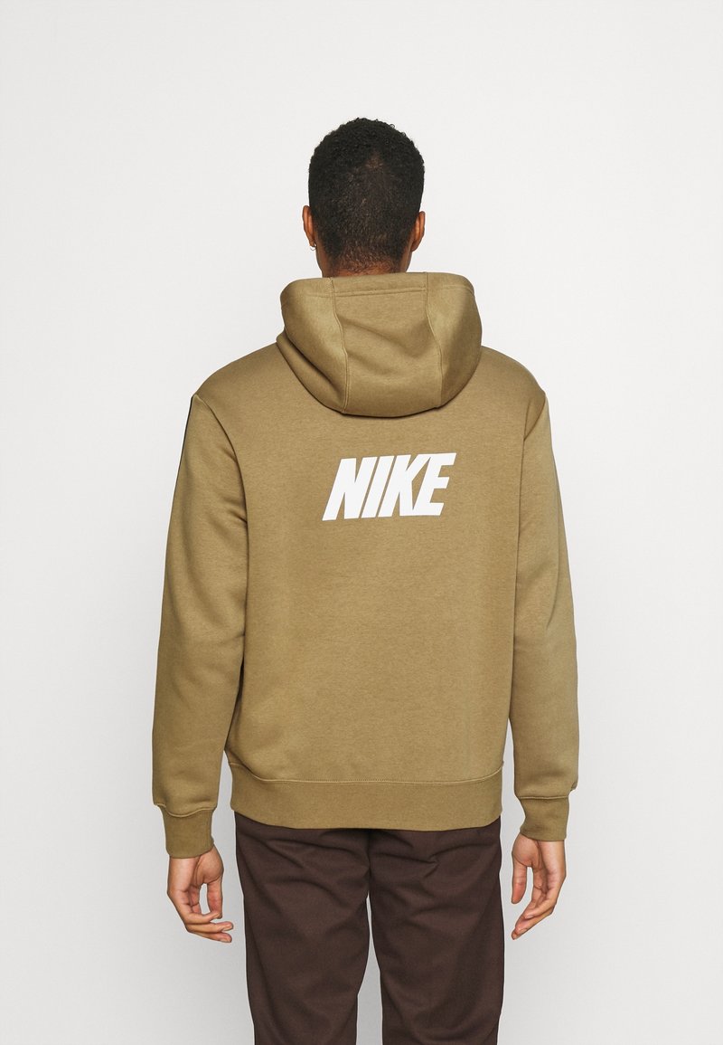 Sudadera con capucha color caqui con un gran logo blanco "NIKE" en la espalda, que presenta una textura suave, bolsillo delantero tipo canguro y capucha con cordón ajustable.