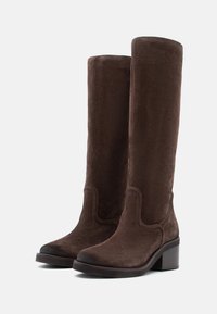 Botas de ante marrón hasta la rodilla con un tacón cuadrado, que presentan una textura suave y costuras decorativas a lo largo del borde superior y el costado.
