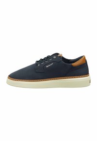 Navy canvas sneakers with brown leather accents, round toe, white rubber sole, and tonal stitching. Features metal eyelets for laces.