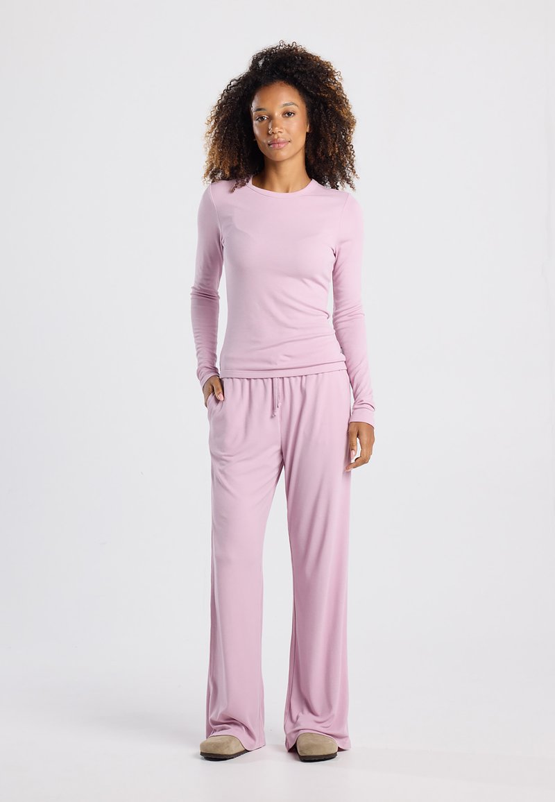 Light pink long-sleeve top and matching loose-fit pants made of soft fabric, featuring an elastic waistband and relaxed silhouette.