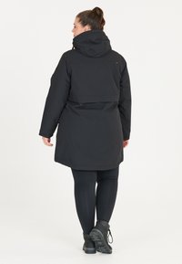 Svart lång kappa med huva, med dragkedja, elastiska ärmslut och rak skärning. Tillverkad av vattentåligt material.