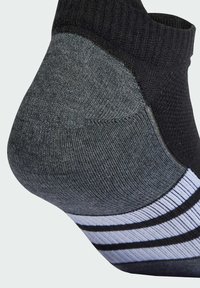 Calcetín negro y gris con talón acolchado, puño acanalado y tres rayas blancas a lo largo del arco del pie para soporte y estilo.
