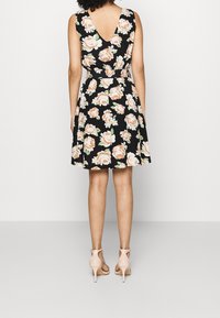 Černé květinové šaty s V-zadním výstřihem, zdobené broskvovými a bílými růžemi. Přiléhavý pas se do šířky rozšiřuje, s délkou po kolena, doplněné nahými podpatky.