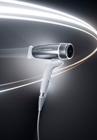 Sèche-cheveux noir et blanc élégant avec le logo "ghd speed", soufflant de l'air, sur un fond sombre parsemé de traits lumineux courbés.