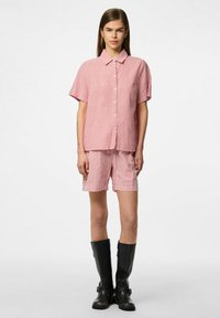 Rood en wit gestreept shirt met korte mouwen en bijpassende shorts, featuring een kraag en knoopsluiting, gecombineerd met zwarte kniehooglaarzen.
