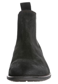 Czarne zamszowe botki Chelsea z okrągłym noskiem, elastycznymi bocznymi panelami i pętelką z tyłu. Płaska gumowa podeszwa, minimalne detale przeszycia.