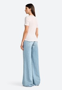 Light pink and white striped short-sleeve top paired with high-waisted, wide-leg light blue denim jeans, featuring a relaxed fit and visible stitching.