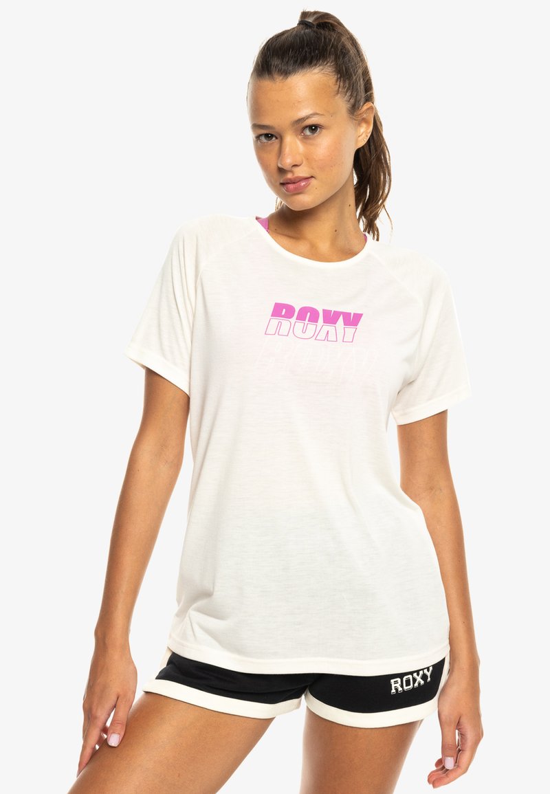 Witte T-shirt met korte mouwen met een roze "ROXY" graphic, gecombineerd met zwarte shorts met witte details en "ROXY" branding aan de zijkant.