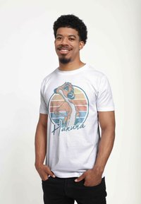Hvid bomulds t-shirt med et farverigt grafik af en tegneserie meerkat og ordet "Hakuna." Korte ærmer, crew neck design.