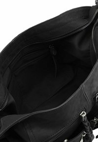 Intérieur d'un sac à main en cuir noir avec plusieurs poches zippées, texture lisse et accents en métal argenté. Doublé en tissu noir.