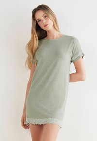 Camisón corto verde hecho de una tela suave, con mangas cortas y acabados de encaje en los puños y un dobladillo de encaje con puntilla en la parte inferior.