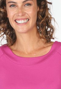 Rosafarbenes, strukturiertes Oberteil mit weitem Halsausschnitt und kurzen Ärmeln, das einen lässigen Schnitt und dezente Stickdetails aufweist.