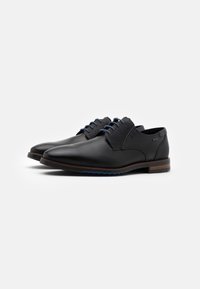 Chaussures en cuir noir au design épuré, avec des accents bleus, un col en tissu en maille et une semelle marron texturée.