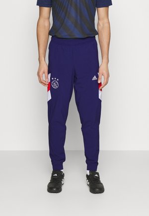 Marineblaue Sporthosen mit weißen und roten Seitenakzenten, versehen mit einem gestickten Logo und Sternen, abgeschlossen mit elastischen Bündchen.
