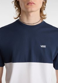 Námořnická a bílá tričko s barevnými bloky vyrobené z bavlny, s kulatým výstřihem a malým bílým logem "VANS" na hrudi.
