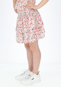 Blomsterprint, lagdelt nederdel med smocket bodice i lyse farver. Sammen med chunky hvide sneakers med røde og marineblå accenter.