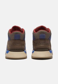 Zapatillas altas con parte superior de textil en tonos marrón, azul y rojo, con un talón de cuero texturizado, cuello acolchado en el tobillo y suelas de goma beige.