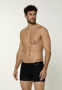 Boxer da uomo neri con una morbida cintura elastica, caratterizzati da un logo discreto nella parte frontale, forma aderente e texture liscia.