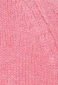 Tissu tricoté rose présentant une surface texturée et douce avec un motif uniforme et des fibres visibles, adapté pour des vêtements ou des accessoires.