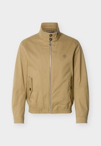 Μπεζ τζάκετ με φερμουάρ και όρθιο γιακά, δύο μπροστινές τσέπες με κουμπιά, ελαστικό τελείωμα και μικρό κεντητό λογότυπο στο αριστερό στήθος.