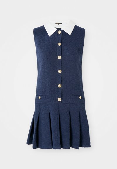 Rochie fără mâneci, de culoare bleumarin, cu un guler alb, având un închidere cu butoane la față, două buzunare laterale și un design cu fustă plisată. Țesătură texturată.