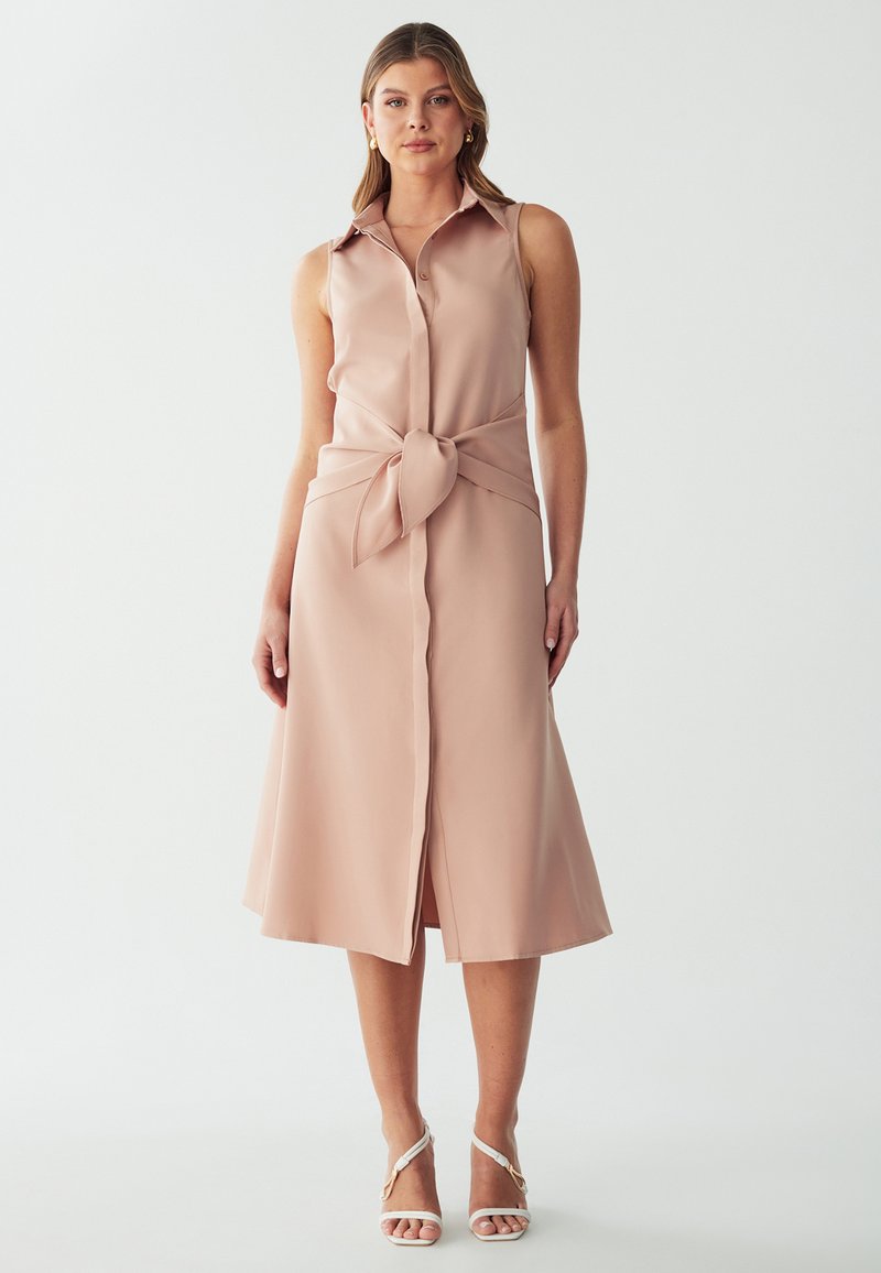 Knie-langes, ärmelloses Kleid aus leichtem rosa Stoff mit Kragen, Frontknöpfen und einer gebundenen Detail an der Taille. Glatte Textur.
