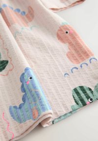 Kokvilnas audums ar jautru dinozauru un veģetācijas rakstu maigos pasteļa toņos, ar teksturētu virsmu un apstrādātām malām.