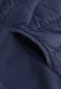 Padded navy jacket interior with smooth lining and quilted texture. Features sewn label and contrasting fabric at the hem.