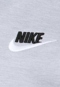 Material gri cu o textură netedă, având un logo "NIKE" negru și un swoosh alb, ambele brodate pe suprafață.