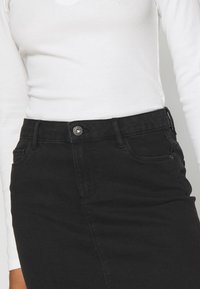 Czarna spódnica dżinsowa z zapięciem na guziki, pięcioma kieszeniami i dopasowanym krojem. Materiał ma gładką teksturę z lekkim streczem.
