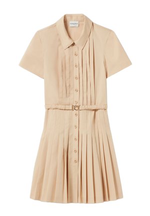 Vestido corto de manga corta en un tono beige claro, con cuello, botones frontales y falda con pliegues. Incluye una cintura ceñida con un cinturón de hebilla circular en tono dorado.