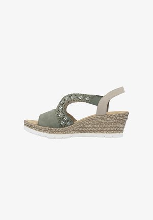 Sandales vertes à talon, avec un design floral découpé, en matériau suédé, et une semelle intermédiaire en paille tissée. Présente une bride de talon beige et une semelle blanche.