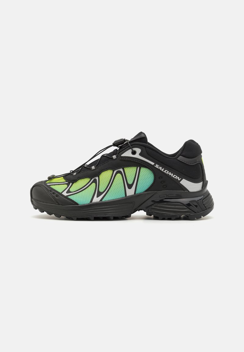 Zapatillas de running de malla negras y verdes con una superficie texturizada, cordones elásticos y un diseño de suela prominente para tracción y soporte.