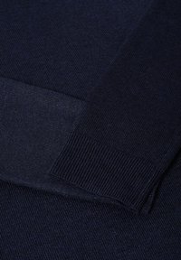 Granatowy, dziany sweter z ribbowymi mankietami i pasem, o miękkiej fakturze i gładkim splocie. Materiał wydaje się lekki i przytulny.