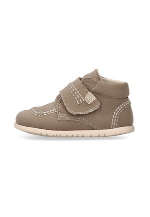 Zapato marrón para niño pequeño con dos correas de velcro, detalles de costura blanca y una suela flexible beige, mostrado desde el lado exterior.